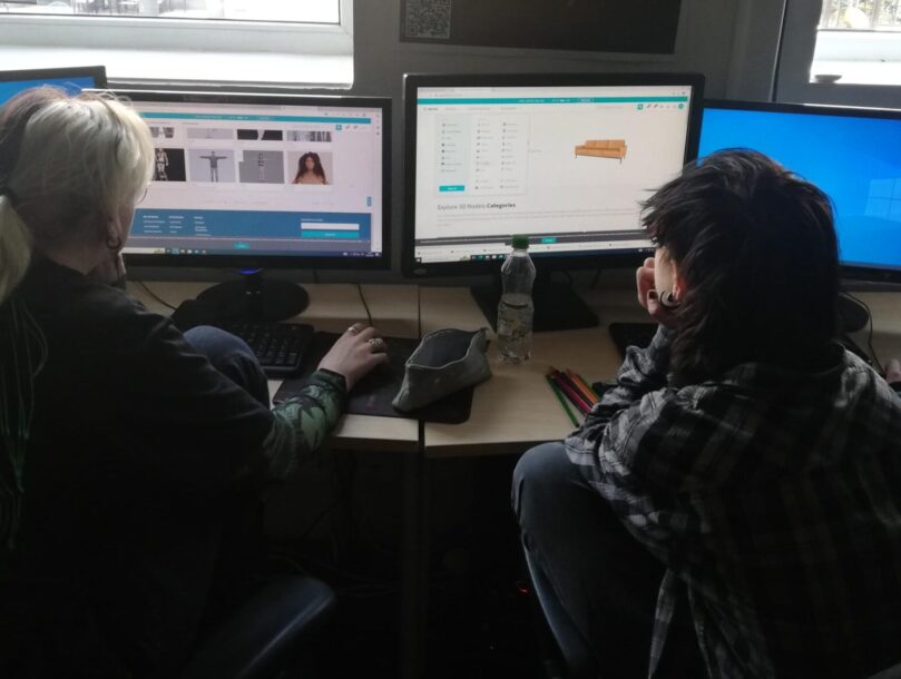 Two people are sitting at a computer.
