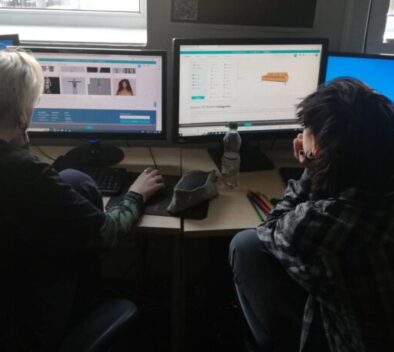 Two people are sitting at a computer.