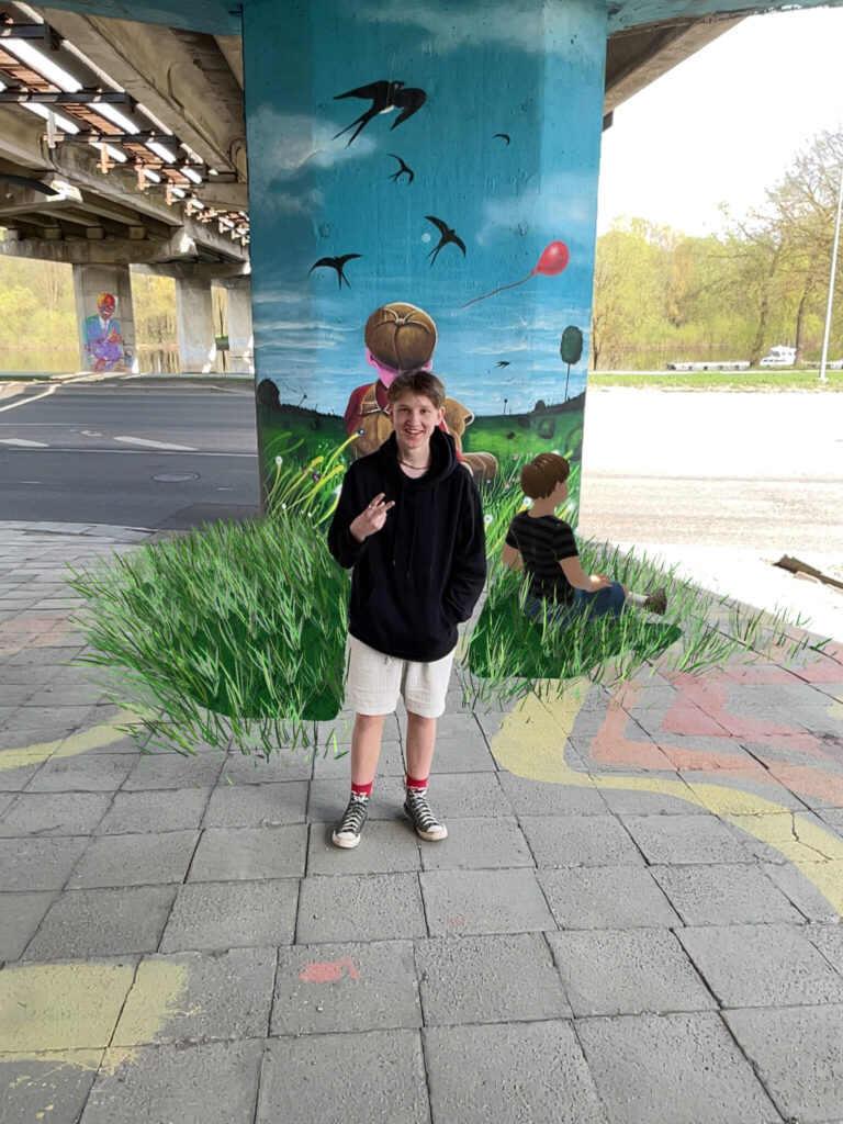 Young boy standing in front of mural.