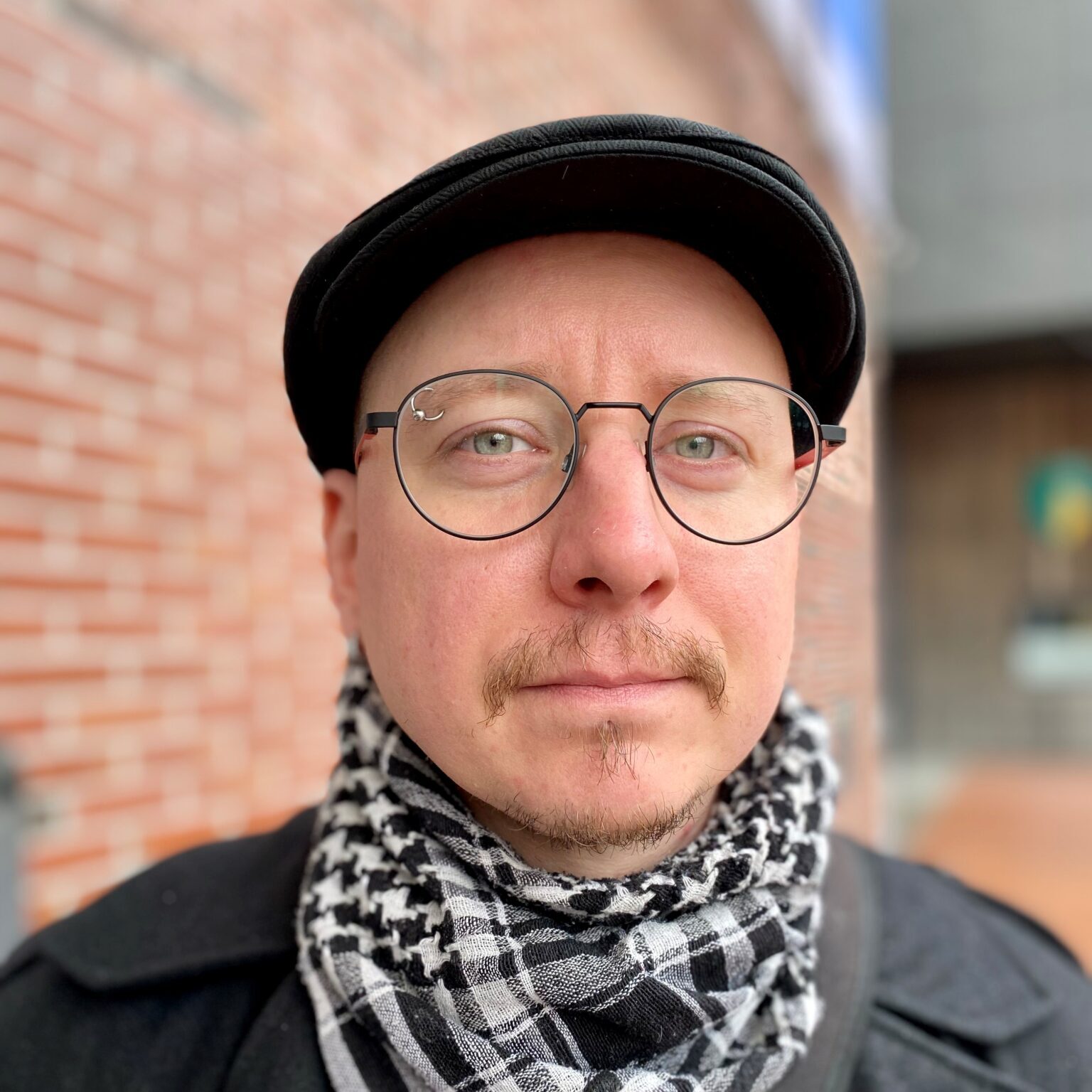 Man with glassess, hat and mustasch. Mikko Röman.