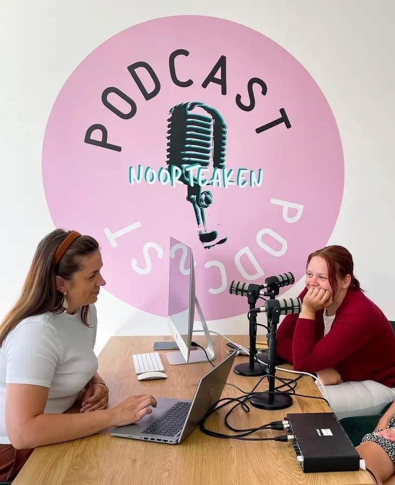 Two woman sitting on desk and making a podcast.
